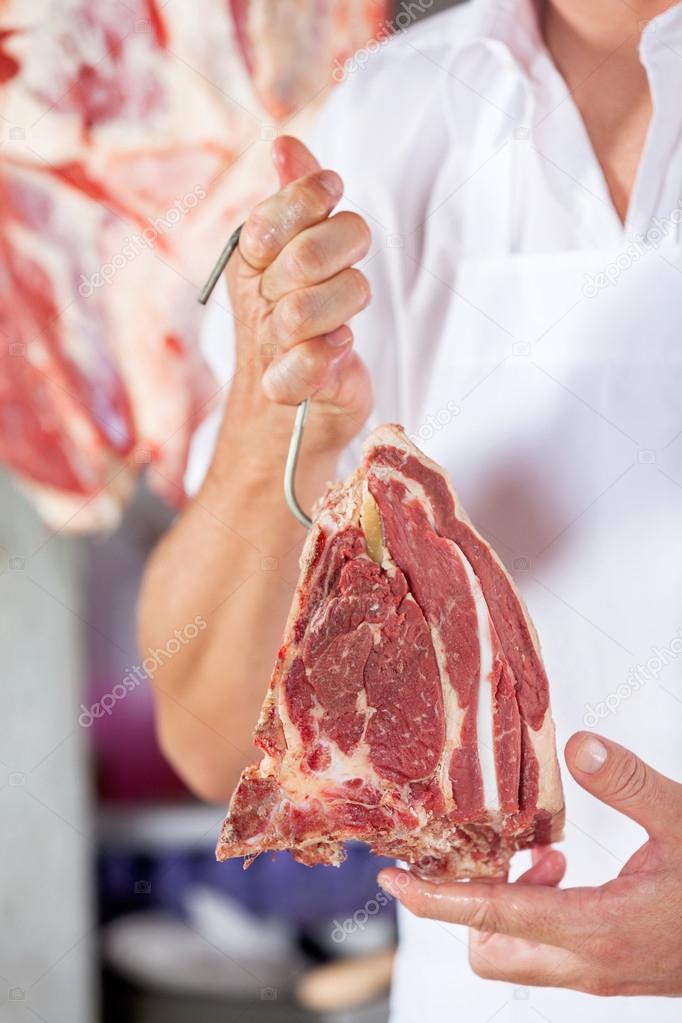 Butcher Holding Raw Meat With Hook