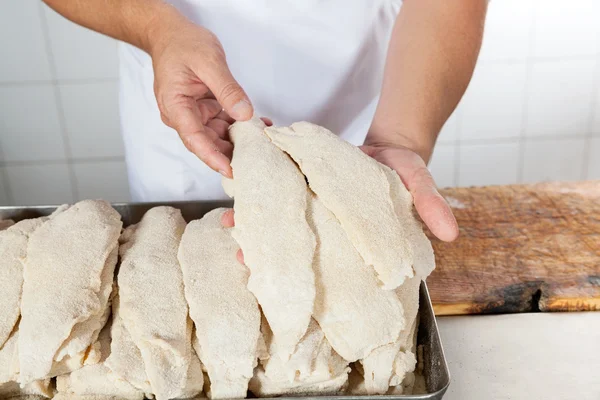 Macellaio che tiene pezzi di carne ricoperti di farina — Foto Stock