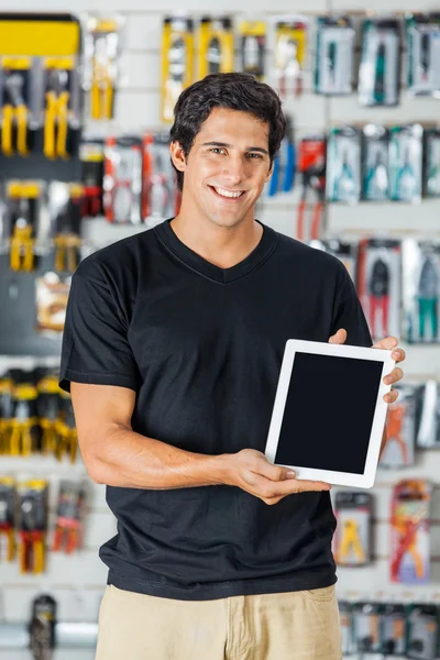 Hombre sonriente que presenta la tableta digital en la tienda de hardware — Foto de Stock