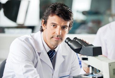Laboratuarda mikroskop kullanarak erkek bilim adamı