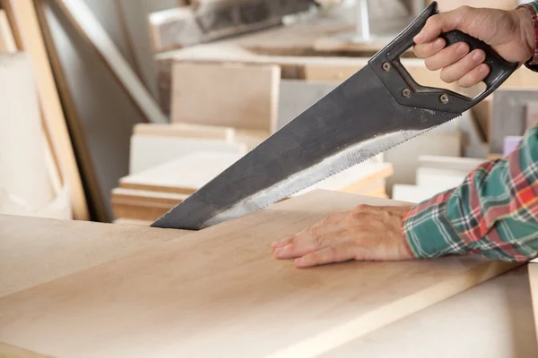 Tablón de madera de corte de carpintero con sierra de mano — Foto de Stock