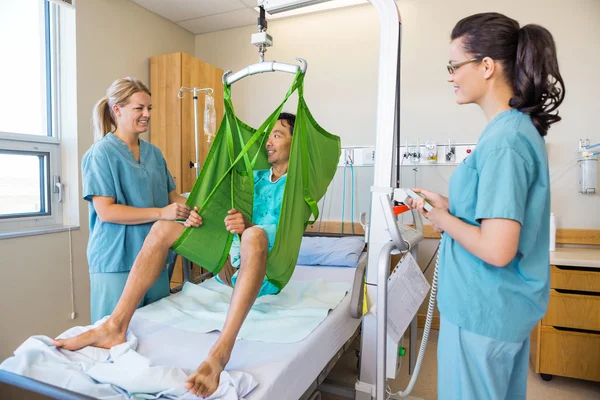 Verpleegkundigen kijken patiënt zittend op doek van hydraulische Lift — Stockfoto