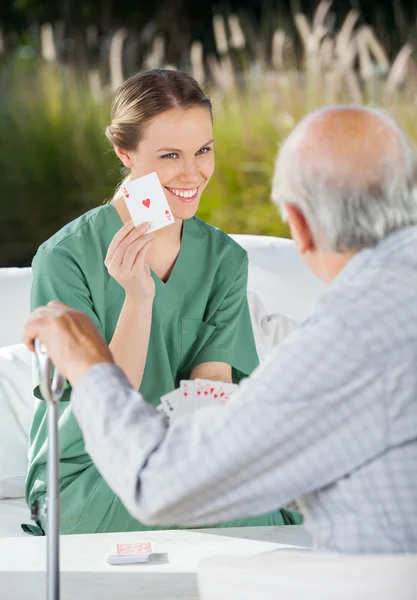 Glimlachend vrouwelijke Caretaker aaskaart tonen aan Senior Man — Stockfoto