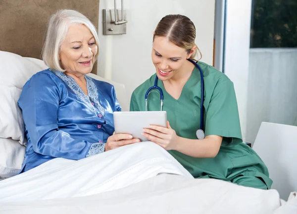 Krankenschwester und Seniorin benutzen Tablet-PC im Schlafzimmer — Stockfoto