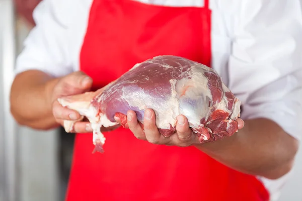 Мясник держит мясо в магазине — стоковое фото