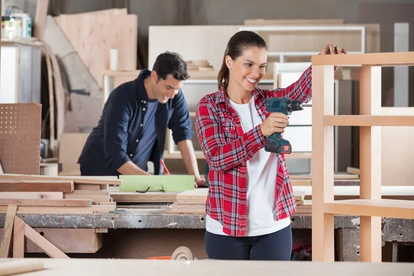 Tischlerin bohrt Holz in Werkstatt — Stockfoto