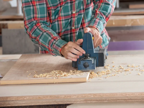 Carpinteiro usando plaina elétrica na prancha de madeira — Fotografia de Stock