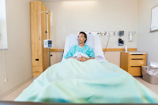 Paciente masculino reflexivo que retrocede en la cama del hospital —  Fotos de Stock