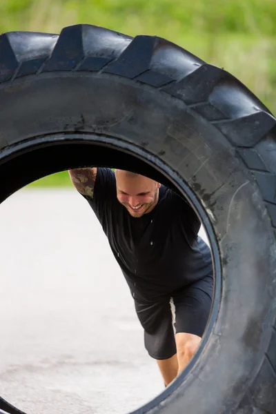 Atleet opheffend groot trekker Tire op straat — Stockfoto