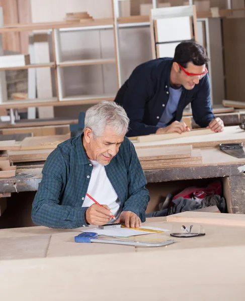 Carpenter Working On Blueprint At Workshop — Stock Photo, Image