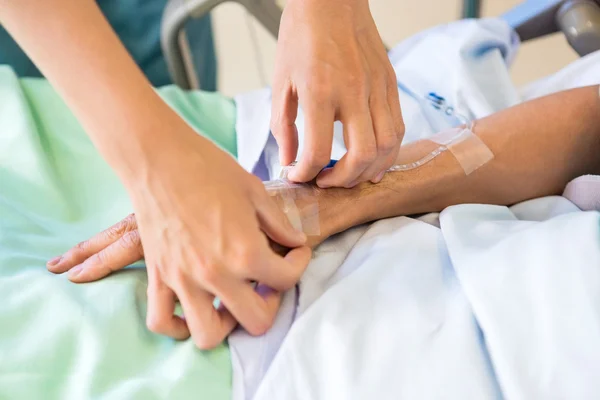 Enfermera adjuntando goteo IV en la mano de los pacientes masculinos — Foto de Stock