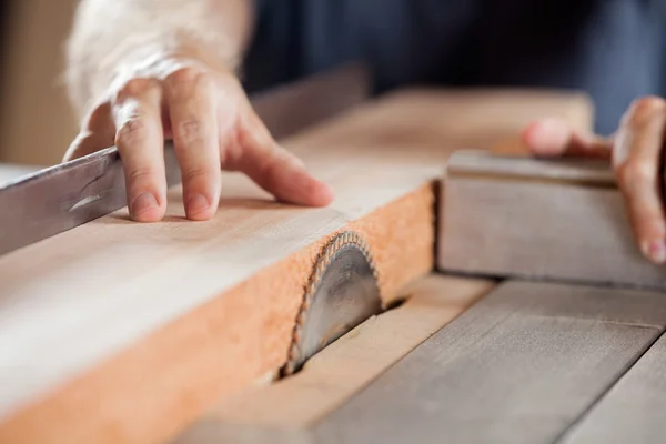 Carpinteiros mãos cortando madeira com tablesaw — Fotografia de Stock