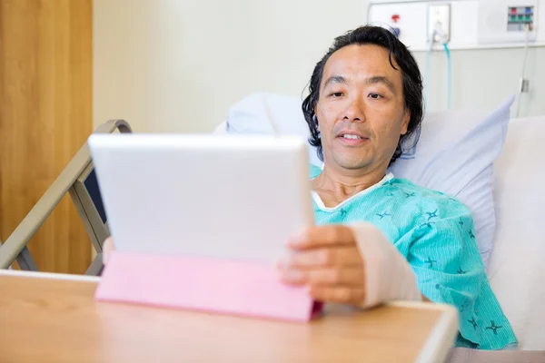 Paciente usando comprimido digital enquanto se revestindo na cama do hospital — Fotografia de Stock