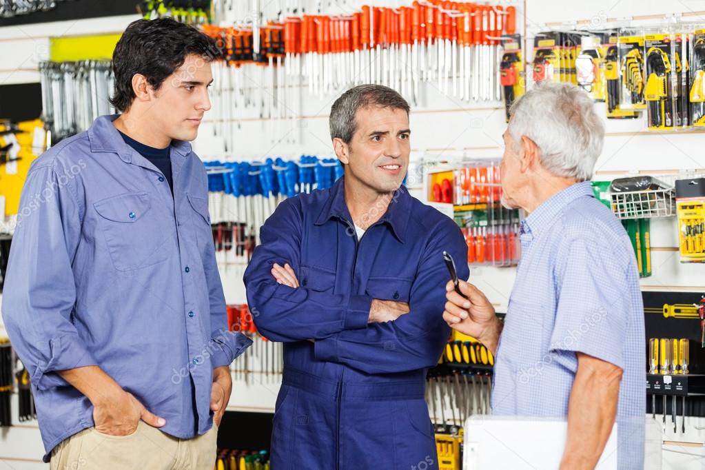 Worker Communicating With Customers In Hardware Shop