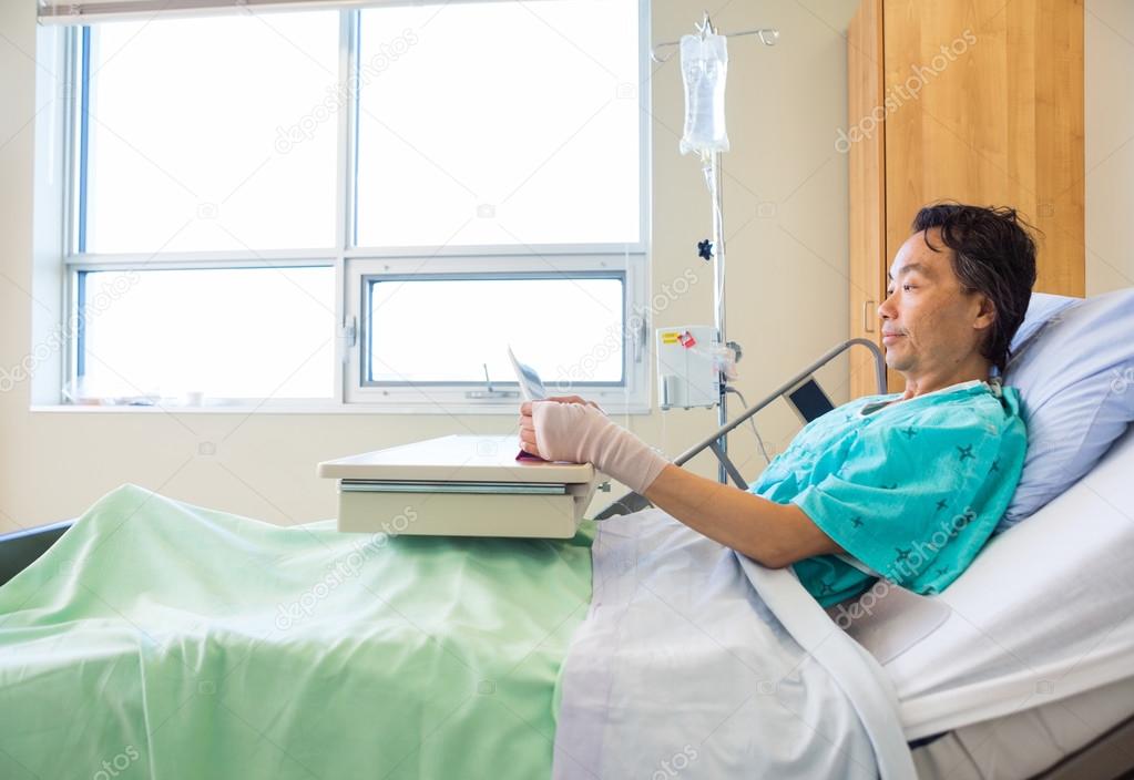 Patient Using Digital Tablet On Hospital Bed