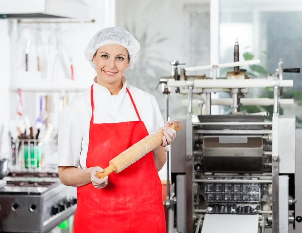 Leende kvinna kock anläggning brödkavel i kök — Stockfoto