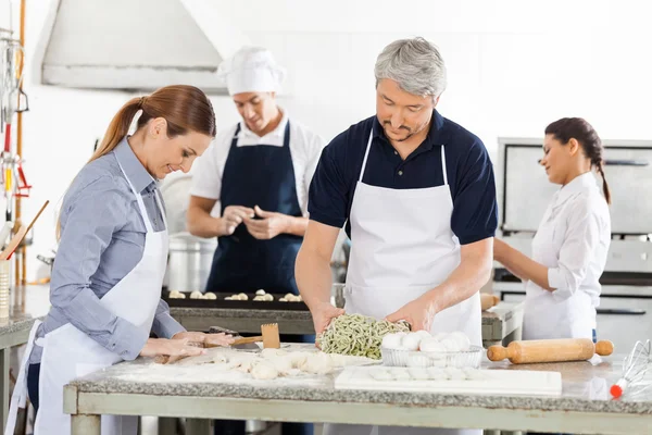 Chefs preparando macarrão juntos na cozinha — Fotografia de Stock