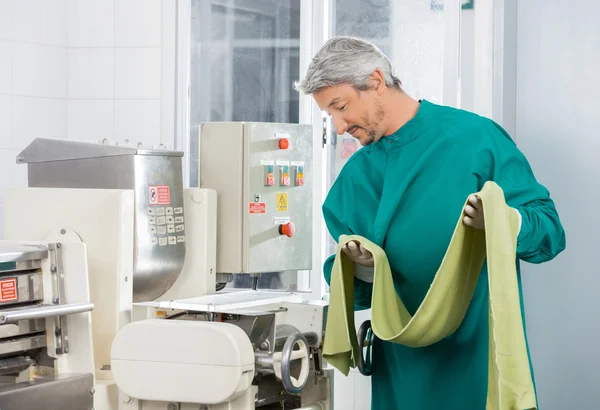 Koch schaut auf Maschine, während er Spaghetti-Nudelblätter in der Hand hält — Stockfoto