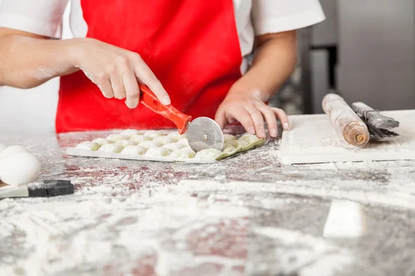 Chef feminino corte Ravioli Pasta no contador bagunçado — Fotografia de Stock