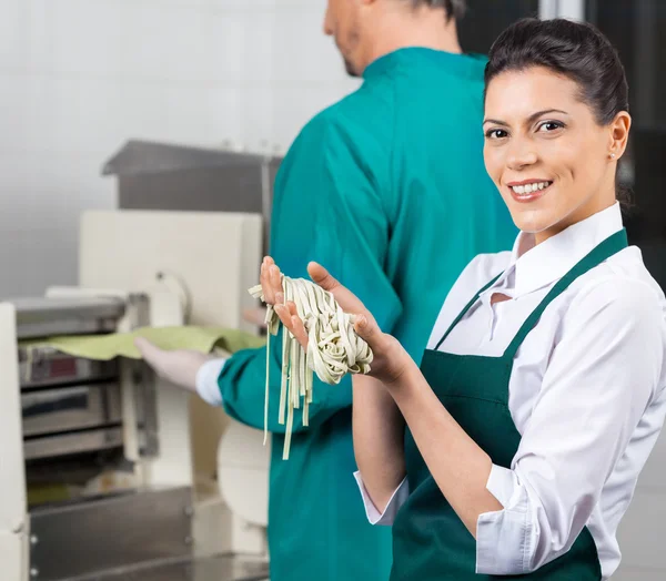 Chef feliz sosteniendo pasta fresca de espaguetis en la cocina — Foto de Stock