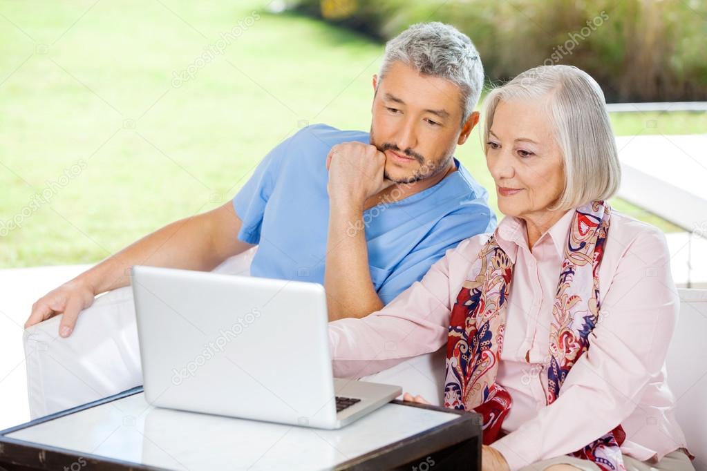 Male Caretaker And Senior Woman Using Laptop