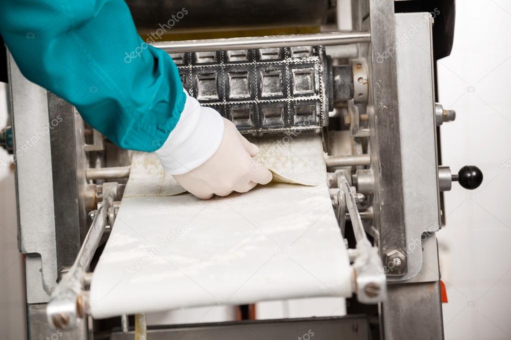 Chefs Hand Removing Ravioli Pasta From Machine