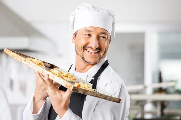 Chef feliz sosteniendo pequeñas pizzas en la bandeja para hornear —  Fotos de Stock