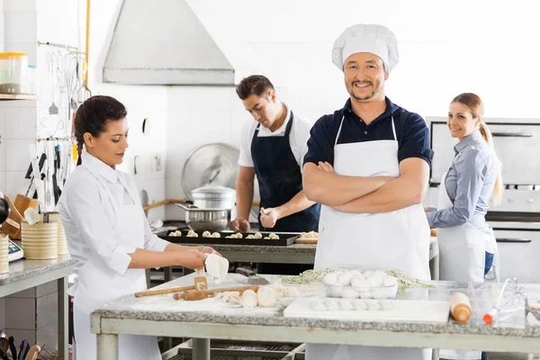 Pewny siebie, Chef stały ręce skrzyżowane podczas kolegów przygotowanie — Zdjęcie stockowe