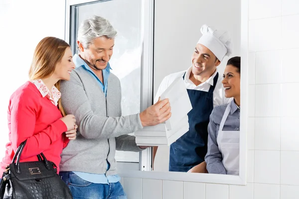 Pareja feliz comprando un paquete de pasta a los chefs —  Fotos de Stock