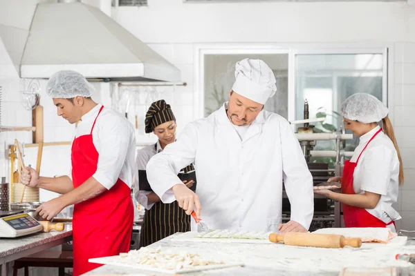 Chefs cocinando pasta juntos en la cocina — Foto de Stock