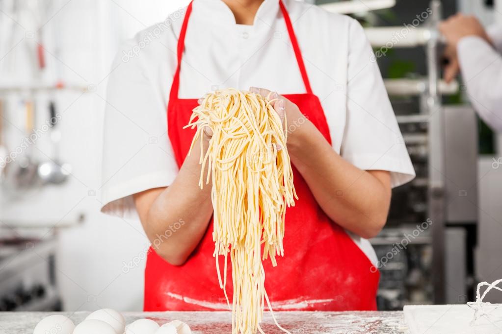 Midsection Of Chef Holding Spaghetti Pasta At Counter