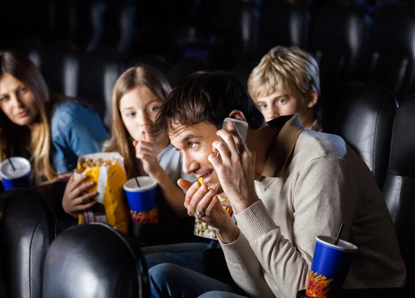 Famille en colère à la recherche à l'homme en utilisant le téléphone mobile dans le théâtre — Photo