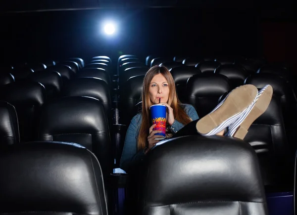 Avslappnad kvinna dricker Cola medan du tittar på film på teater — Stockfoto