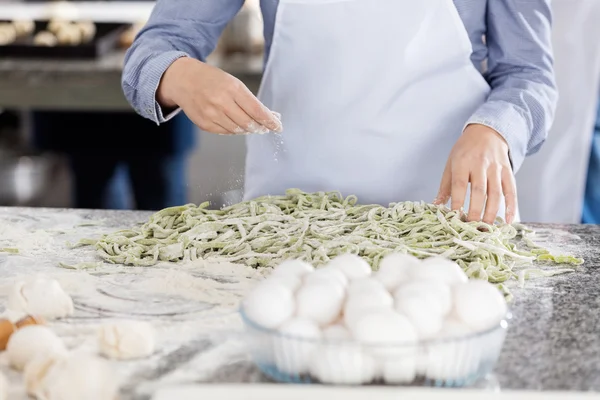 Chef streut Mehl auf Spaghetti-Pasta am Tresen in der Küche — Stockfoto