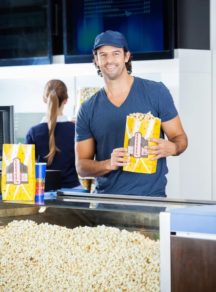 Happy pracovník drží Popcorn Paperbag na tribunu — Stock fotografie