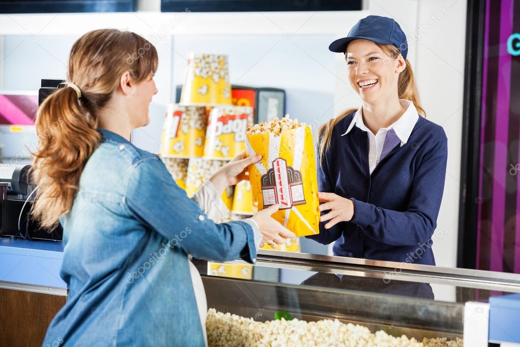 Happy Seller Giving Popcorn To Pregnant Woman At Concession Stan