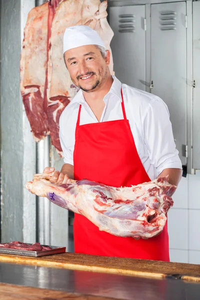 Carnicero macho seguro que lleva carne en la carnicería — Foto de Stock