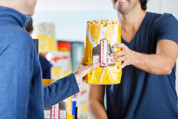 Verkäufer schenkt Mann Popcorn am Konzessionsstand — Stockfoto