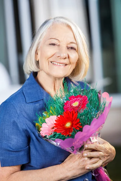 Gelukkig Senior vrouw met boeket bij verpleeghuis — Stockfoto