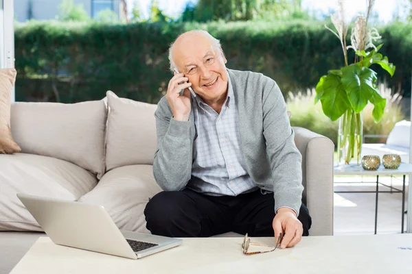 Lächelnder Senior beantwortet Smartphone auf der Veranda des Pflegeheims — Stockfoto