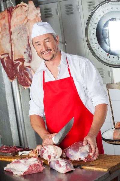 Carnicero feliz cortando carne con cuchillo — Foto de Stock