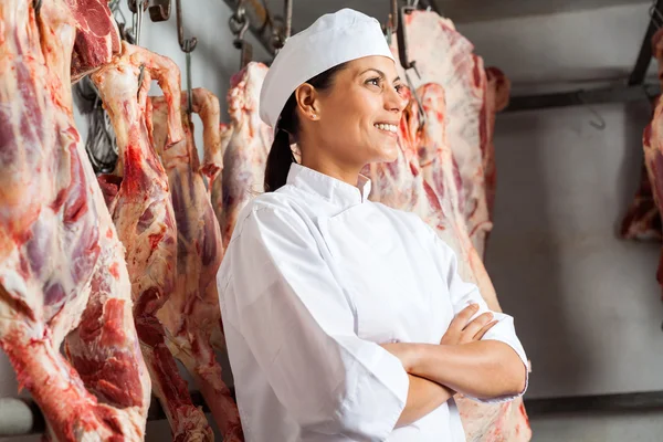 Glückliche Metzgerin steht im Schlachthof — Stockfoto