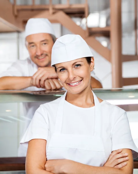 Glückliche Fleischereifachverkäuferin mit Kollegin in Metzgerei — Stockfoto