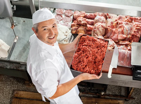Carniceiro confiante segurando carne picada — Fotografia de Stock