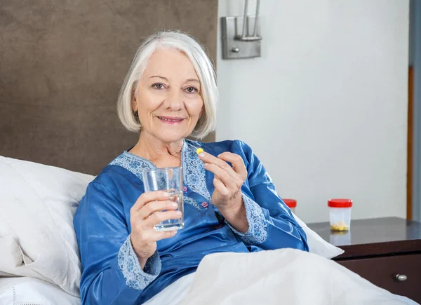 Улыбающаяся пожилая женщина принимает лекарства в доме престарелых — стоковое фото