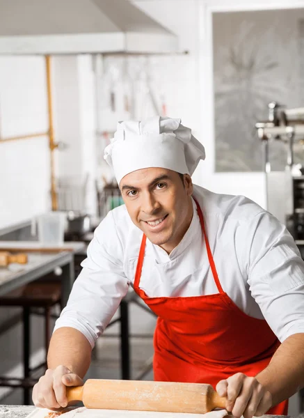 Chef masculino sonriente Rolling Pasta Sheet en el mostrador —  Fotos de Stock