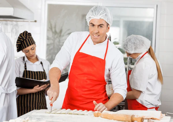 Usmíval se šéfkuchař připravuje Ravioli těstoviny s kolegy v poz — Stock fotografie