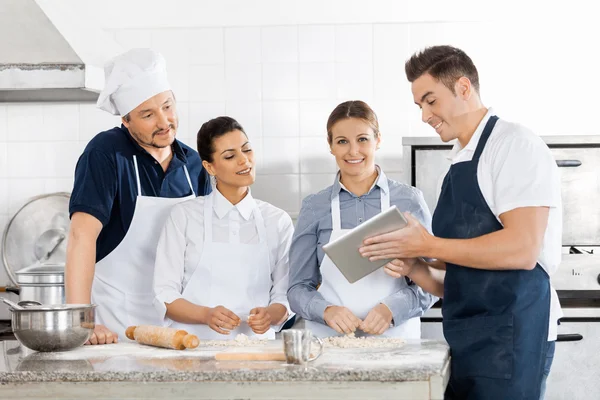 Köche überprüfen Rezept am Tablet-Computer in der Küche — Stockfoto