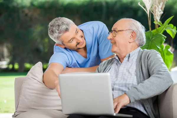 Smiling Nurse Assisting Senior Man In Using Laptop — Stock Photo, Image