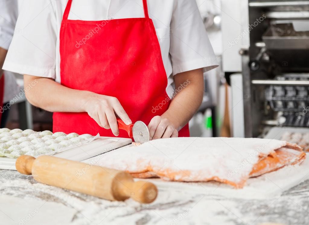 Female Chef Cutting Ravioli Pasta In Commercial Kitchen